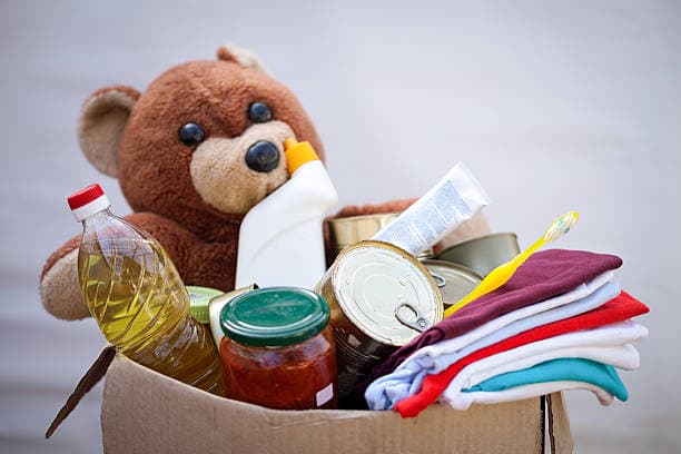 Two hands gently holding a red paper heart, symbolizing community care and support.